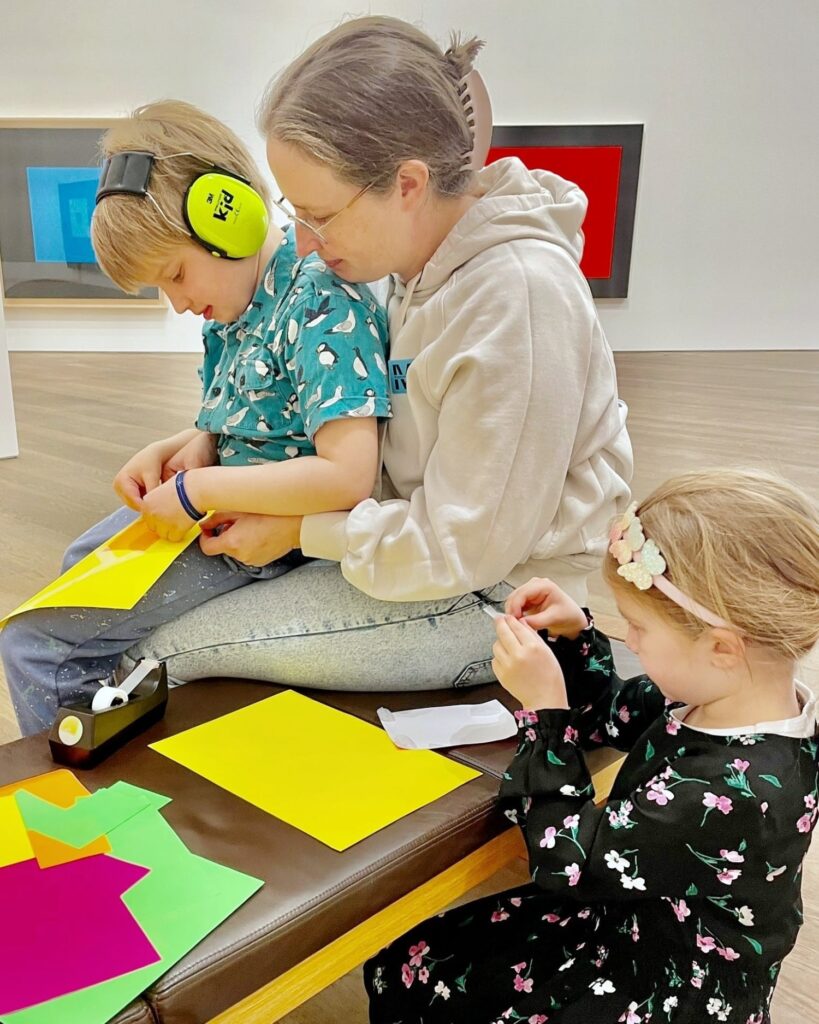 Une femme avec deux jeunes enfants qui s'amusent avec des feuilles de couleur